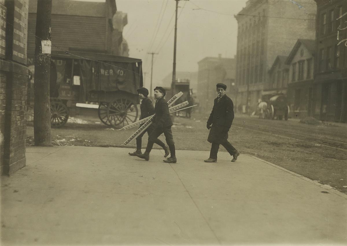LEWIS W. HINE (1874-1940) Boys walking and carrying boards.